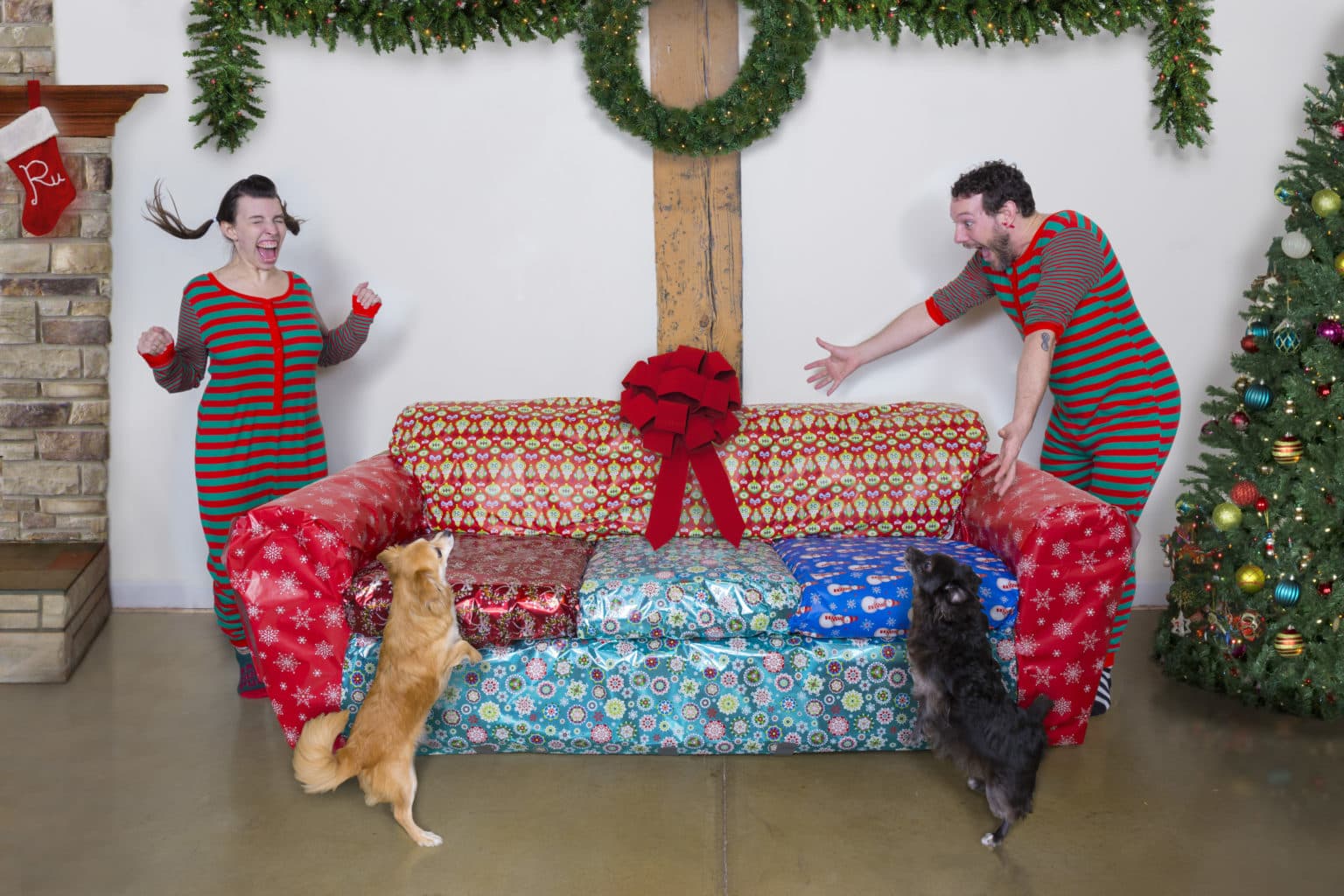 Lauren and Deven with the couch inside a large wrapped present.