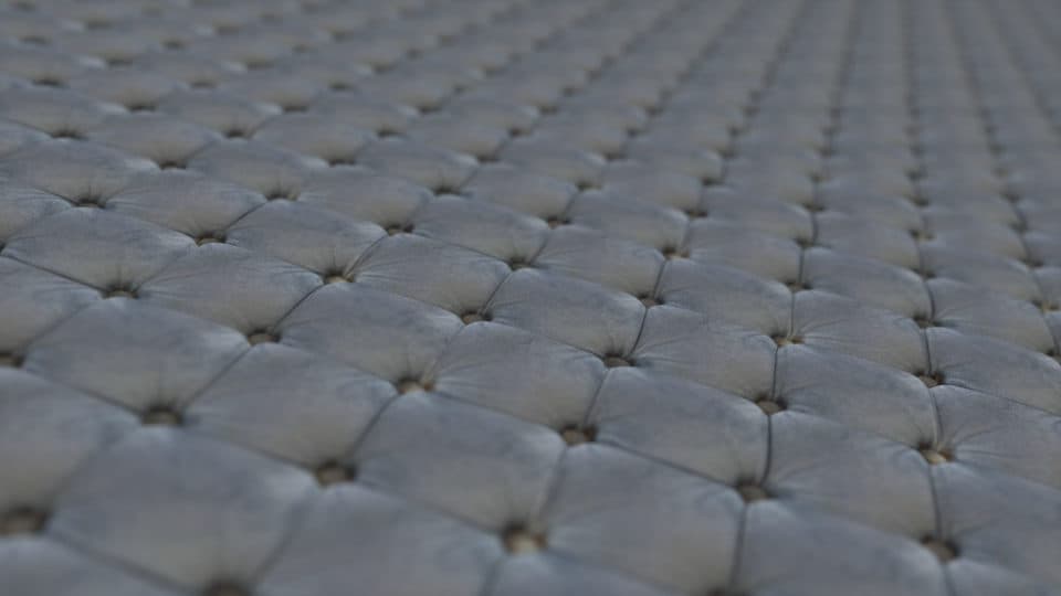 Rendered cushion covered with a repeating patterned fabric material.